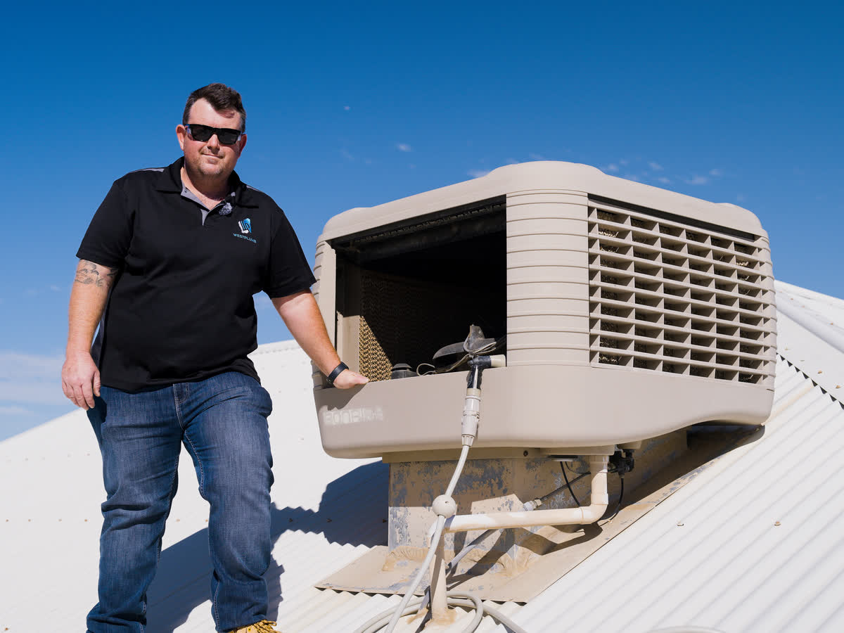 Brent beside an evaporative air conditioner on a Perth roof